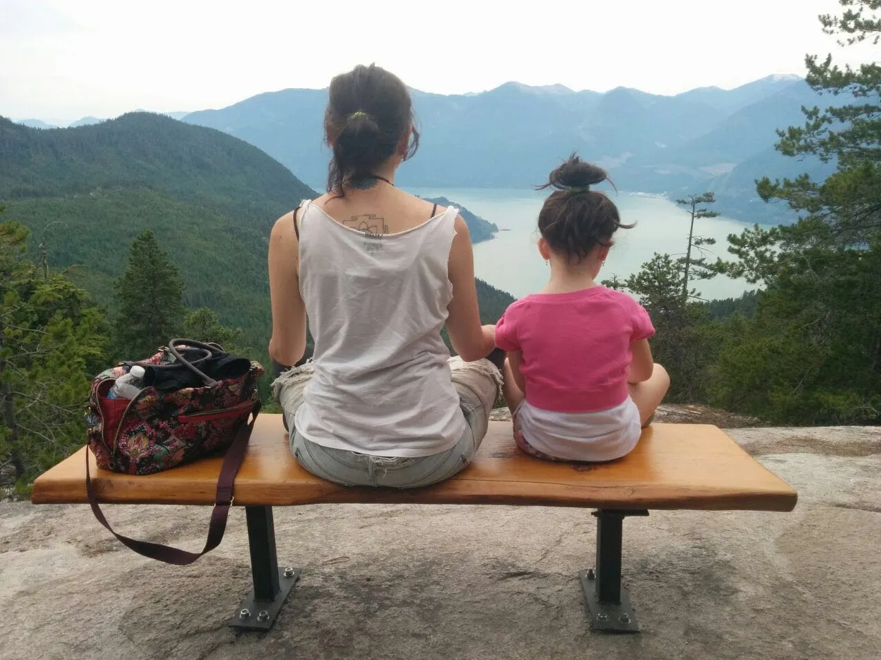 אמא וילדה יושבות על ספסל, מצולמת מהגב